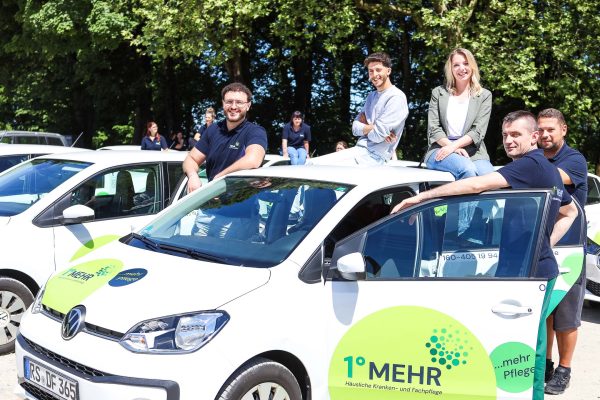 Teambild von 1gradmehr am Parkplatz mit den 1gradmehr Firmenautos für Ambulante Pflege